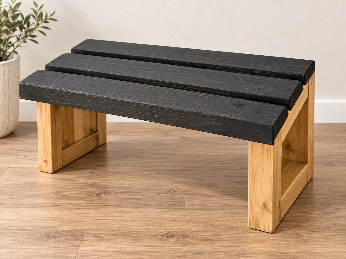 Styled image of handcrafted rustic bench with black slatted top and natural wood base